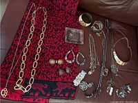 Overview of the full lot showing the animal print scarf underneath and multiple jewelry pieces arranged on a brown surface including bracelets, rings, necklaces, cufflinks, and earrings.