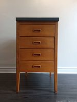 Front view of vintage four drawer storage chest showing wood craftsmanship and integrated handles.