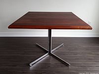 Front view of square rosewood tabletop and chrome cross base
