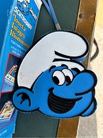 Close-up image of blue Smurf face shaped radio or speaker showing some wear.