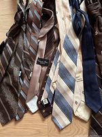 Photo showing seven vintage ties laid out on floor with various neutral colors and patterns