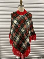 Overall front view of the plaid mohair fringe cape on a mannequin showing colors and fringe detail.