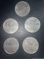 Top view of five 1982 Canadian commemorative coins, showcasing detailed historical scenes and inscriptions.