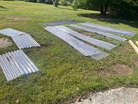 Overview of multiple clear corrugated plastic panels laid on grass, showing variety of lengths