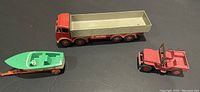 Photo of all 3 Dinky diecast vehicles showing red/beige Fodens truck, green/beige boat on trailer, and red jeep with windshield removed.