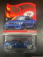 Front view of blue 2006 BMW M3 Hot Wheels diecast in blister pack with red flame Hot Wheels packaging.