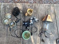 Overview of all items in lot on wooden surface: small black desk fan, ceramic bowls, pitcher, 2 clamp lights, decorative lamp shade