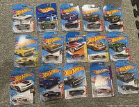Full lot showing 12 Hot Wheels muscle cars in original sealed packaging, organized in a 3x4 layout on carpet background.