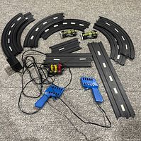 Full overview of track pieces, cars, controllers, and power supply arranged on carpet
