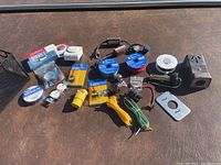 Various electrical components including electrical tape rolls, wire, connectors, wire ties, adapters, and outlets spread out on a surface.
