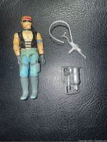Full view of GI Joe figure with both weapon accessories on black background.