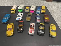 Photo showing all 14 1/64 scale vintage Majorette diecast vehicles arranged in rows, showcasing variety of colors and models including cars and camper trucks.
