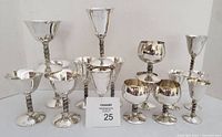 Full view of all 16 silver plated stemware pieces arranged in groups by size and type.