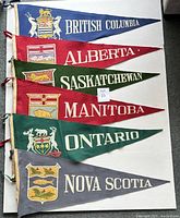Six large felt pennants representing Canadian provinces, laid flat together for overview.