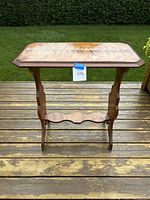 Front view of the antique wooden side table showing the overall structure, scalloped shelf, and leg design.