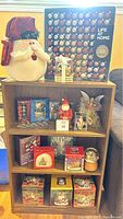 Photo of vintage Santa tree topper, assorted glass ornaments in packaging, and multiple small holiday figurines and decorations on a bookshelf
