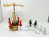 Photo of the entire lot showing wooden candle carousel with 4 red candles and porcelain nativity figures plus two small Christmas trees