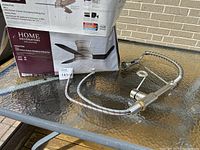 Kitchen faucet with stainless steel finish and flexible spring coil sprayer on glass table outdoors