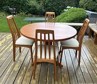 Round teak dining table assembled with four chairs on deck