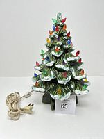 Full view of vintage ceramic lighted Christmas tree with electric cord and multicolored bulbs.