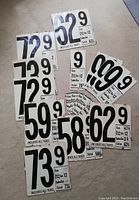 Photo showing multiple cardboard gas price cards with prices ranging from 58.9 to 99.9 cents per gallon. Several cards include tax details.