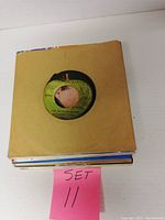 Stack of 25 vinyl records labeled as Set 11 with paper sleeves in various colors and conditions.