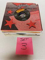 Stack of 25 45 RPM vinyl records in collectible sleeves marked as Set 3.