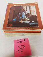 Stack of vinyl records with Carole King 'It's Too Late' visible on top with full-color album cover.