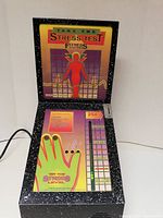 Front view of the Stress Tester arcade machine showing illuminated top screen, green hand graphic, and coin slot.