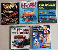 Front covers of all five collectible reference books laid out on carpet, showing titles and cover imagery of toy cars and trucks.