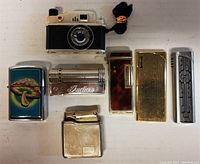 Top view of six vintage lighters showing various designs and shapes including camera shape and mushroom art.