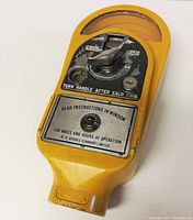 Full top and front view of vintage yellow Rhodes parking meter showing coin mechanism and instructions plate.