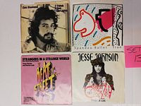 Four vinyl 45 RPM records with original picture sleeves including Cat Stevens, Spandau Ballet, Heat Street, Jesse Johnson visible from front.