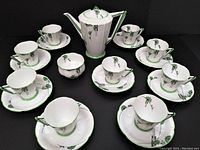 Displayed full set showing coffee pot, sugar bowl, cups and saucers with Art Deco green and black pattern on white porcelain.