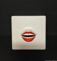 Front view showing white plastic square radio with 3D red lips and teeth.