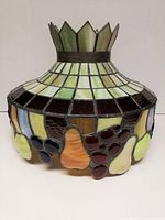 Front view of the vintage stained glass lamp shade showing the colorful fruit motifs around the bottom edge and the crown-like top.