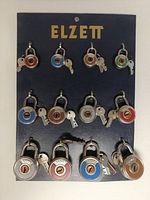 Front view of original Elzett store display board with 12 round padlocks, each with colored rings and paired keys.