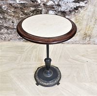 Front view of the small round Art Deco pedestal table showing the polished white marble inset top and dark wooden surround with cast metal base.