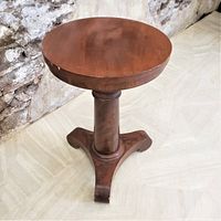 Full view of the antique organ stool showing the round wooden top and tripod leg base with adjustable height post.