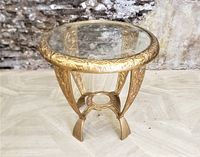 Front view showing detailed foliage designs on the cast iron table rim and legs with round glass inset top.