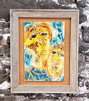 Frontal view of framed pottery tile mounted with burlap backing and pine frame, showing abstract twin-face design in yellow, orange and blue glazes.