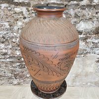 Front view of large Handerbeit pottery floor vase showing incised leaf and linear patterns on terracotta body.