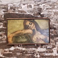 Frontal view of the framed oil painting showing the reclining nude female and gallery frame hung on stone wall.