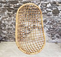 Front view of suspended rattan egg hanging chair against stone-patterned backdrop