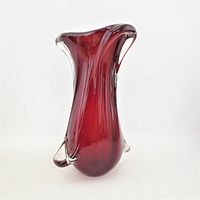 Front angled view of the deep ruby red art glass vase with clear glass ribbons wrapping around the body and flared top edge.