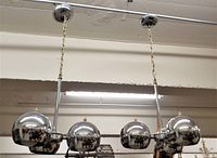 Frontal view of two chrome ball ceiling fixtures hanging from chains and round ceiling caps