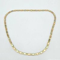 Full view of tricolor gold link necklace laid out flat