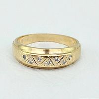 Front view of yellow gold band showing five round diamonds set in milgrain-edged triangular bezels.