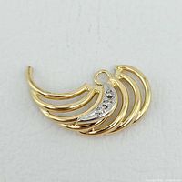 Front view of fan-shaped gold pendant showing openwork design and diamond-accented white gold section