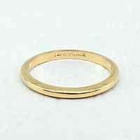 Front view of slim yellow gold band ring lying flat
